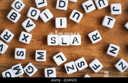 Kleine weiße und schwarze Perlenwürfel auf Holzbrett, Buchstaben in der Mitte buchstabieren SLA - Service Level Agreement Konzept Stockfoto