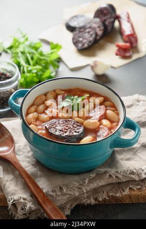 Asturiana traditionelle Fabada mit Haricot, Blutwurst auf braunem Hintergrund. Vertikale Ausrichtung. Leckeres, traditionelles spanisches Abendessen. Stockfoto