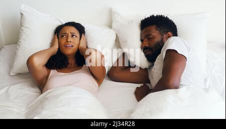 Ich liebe dich, aber ich wünschte, das Schnarchen könnte aufhören. Eine kurze Aufnahme einer schönen Frau, die sich ärgerte, als ihre hübschen Männer zu Hause im Bett schnarchen. Stockfoto