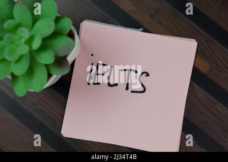 IELTS schreiben auf Haftnotizen isoliert auf Holztisch. Stockfoto