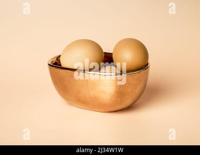 Ostern goldgefärbte Eier in Schüssel. Religiöses Frühlingsferienkonzept auf beigefarbenem Hintergrund in modernem Stil. Hochwertige Fotos Stockfoto