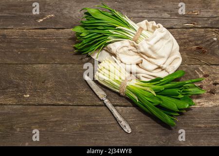 Trauben einer frischen Ernte von Frühlingsramson oder wildem Lauch. Duftende würzige Blätter auf Vintage-Holztisch Hintergrund, hartes Licht, dunkler Schatten, Kopie spac Stockfoto