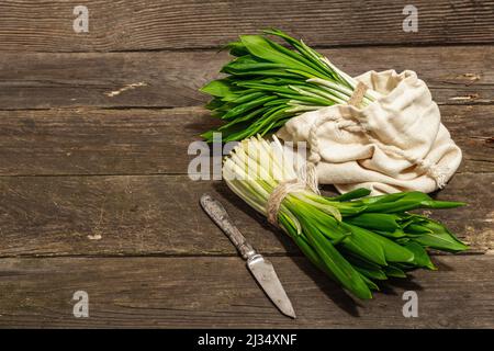 Trauben einer frischen Ernte von Frühlingsramson oder wildem Lauch. Duftende würzige Blätter auf Vintage-Holztisch Hintergrund, hartes Licht, dunkler Schatten, Kopie spac Stockfoto