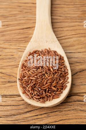 Roher roter Vollreis in einem Löffel über dem Holztisch. Stockfoto
