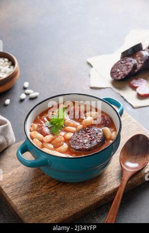 Asturiana traditionelle Fabada mit Haricot, Blutwurst auf braunem Hintergrund. Vertikale Ausrichtung. Leckeres, traditionelles spanisches Abendessen. Stockfoto