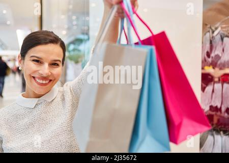 Glückliche junge Frau zeigt stolz ihre Einkaufstaschen nach dem Einkaufen im Einkaufszentrum Stockfoto