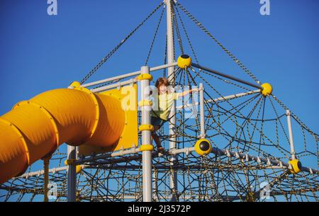 Kind auf Rutsche Spielplatz. Kid boy kletterte auf das Seil Netz, Kinder Wachstum Konzept. Stockfoto