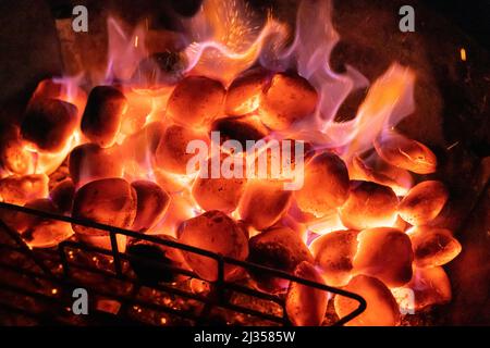 Heiße Kohlen auf einem Grill in der Nacht mit einer Grillvorführen. Konzept: Grillen, Grillen, grillen, Wärme, Grillen, Heiße Kohlen, brennende Kohlen, Hitze, Brennstoff Stockfoto