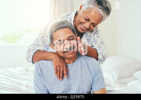 Wow, ich bin heute verwöhnt. Aufnahme eines fröhlichen reiferen Paares, das sich während des Tages auf einem Bett zu Hause hielt. Stockfoto