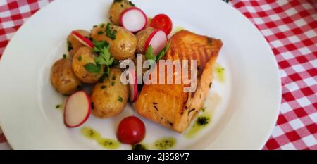 Lachs mit Kartoffeln serviert auf einer Gingham-Tischdecke mit rotem Karomuster Stockfoto