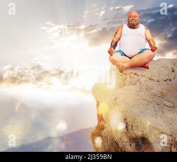 Lustiger Mann mit Bart in Yoga-Position im Freien in einem Berg Stockfoto