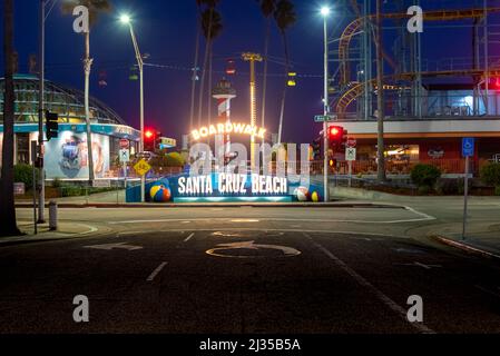 SANTA CRUZ, CA-MAR 31, 2022: Nachtansicht des Santa Cruz Beach Boardwalk, vom Vordereingang mit seinem hellen Neonschild aus gesehen. Der Vintage Seaside am Stockfoto