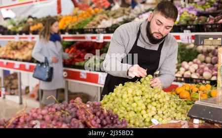 Einkaufsassistent legt Gemüse und Obst an die Theke des Supermarkts Stockfoto
