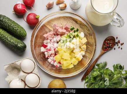 Zutaten für die Zubereitung von leckeren Okroshka auf grauem Hintergrund, Nahaufnahme Stockfoto