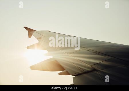 Lasst uns wegfliegen. Ausgeschnittene Aufnahme eines Flugzeugflügels während des Fluges. Stockfoto