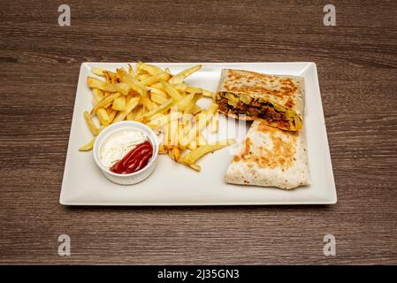 Burrito gefüllt mit Fleisch und Gemüse, garniert mit hausgemachten Chips und Saucen Stockfoto