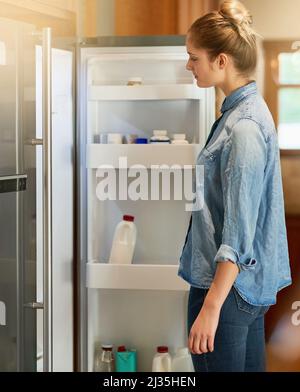 Wenn der Hunger einschlägt Eine kleine Aufnahme einer jungen Frau, die zu Hause in ihren Kühlschrank schaut. Stockfoto