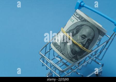 In einen Schlauch gerollte Dollars liegen in einem Einkaufskorb. Stockfoto
