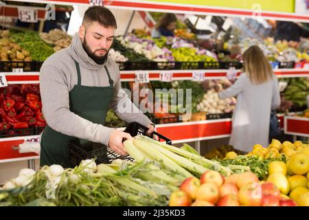 Einkaufsassistent legt Gemüse und Obst an die Theke des Supermarkts Stockfoto