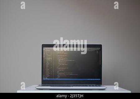 Geöffneter Laptop mit Code auf dem Bildschirm auf dem Tisch Stockfoto