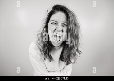 Nahaufnahme Porträt einer verrückten Frau in Zwangsjacke auf weißem Hintergrund. Monochrom. Stockfoto