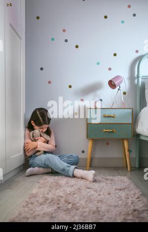 Deprimiert Mädchen umarmt Plüsch Puppe auf dem Boden sitzen Stockfoto