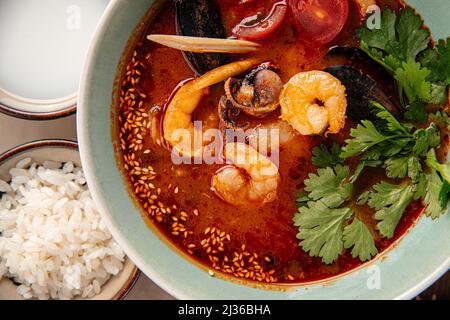 Schüssel mit thailändischen Meeresfrüchten tom Yam Suppe mit Reis Stockfoto