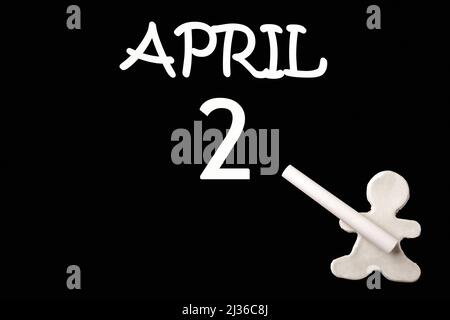 2. Tage im April. Ein kleiner weißer Mann aus Plastilin, der das Datum vom 2. April auf eine schwarze Tafel schreibt. Geschäftskonzept. Bildungskonzept. Frühlingsmonat, Tag des Th Stockfoto
