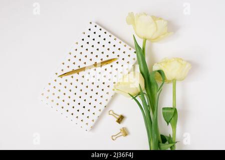 Flach Lay Frühlingsblumen Gelbe Tulpen, Tasse Kaffee weiß leeres Album Notizbuch Schreibfeder auf weißem Hintergrund. Schöne Grußkarte für März 8 Moth Stockfoto