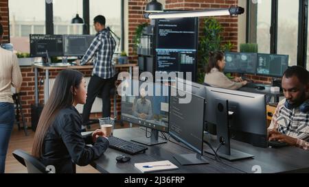 Mitarbeiter des Softwareunternehmens in einer Videokonferenz mit dem Geschäftsinhaber, der im Büro mit dem Team über die Codierung des Projekttermins spricht. Programmierer, der online mit dem Kunden über den Quellcode chatten kann. Stockfoto