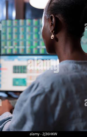 Nahaufnahme eines Experten für den Aktienhandel, der vor einer Multi-Monitor-Workstation sitzt, während er Optionen kauft und verkauft. Maklerfirma Agent Analyse Echtzeit-Marktgraphen und Live-Charts. Stockfoto