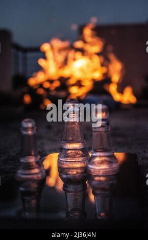 Eine vertikale Nahaufnahme der transparenten Schachfiguren gegen Feuer. Stockfoto