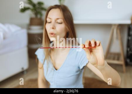 Räucherstäbchen. Kaukasische Frau bläst, hält, genießt Aroma Stick. Stockfoto