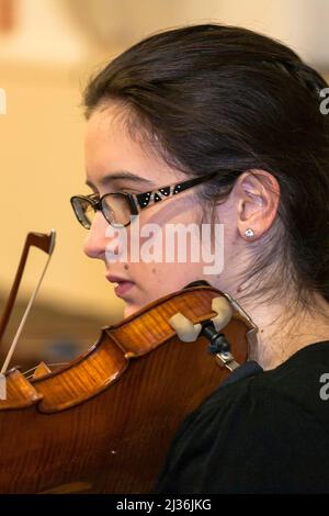 Junge Geigerin voll konzentriert, während sie ein Probestück für Coma Sussex's Festival Concert in der Universität von Chichester, 2018, spielt Stockfoto