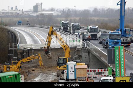 06. April 2022, Mecklenburg-Vorpommern, Tribsees: Auf der Baustelle der abgefahrenen Ostseestream werden auf der fertigen Hälfte der Fahrbahn ein LKW-Kran und LKW für Montagearbeiten und die Lieferung von Komponenten für die zweite Seite der Autobahn, auf der Bagger arbeiten, geparkt. Die Autobahn muss für die Arbeiten wieder für einen Tag komplett gesperrt werden. Die erste Hälfte der Autobahn wurde im Herbst 2021 fertiggestellt, und der Neubau des Abschnitts sollte bis Ende 2023 abgeschlossen sein. Die A20 war 2017 im Sumpf zusammengebrochen und hinterließ eine riesige Stockfoto