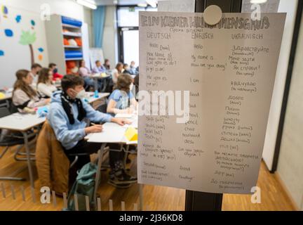 München, Deutschland. 06. April 2022. Kinder aus der Ukraine sitzen morgens in einer Willkommensklasse am Gymnasium Trudering. Auf einem Beitrag hängt eine Notiz mit einer Begrüßung in Deutsch, Englisch und Ukrainisch. Kredit: Peter Kneffel/dpa/Alamy Live Nachrichten Stockfoto