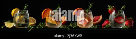 Kalte erfrischende Getränke mit natürlichem Eis in gefrorenen Gläsern. Cocktail-Set mit Zitrone, Orange, Grapefruit und Erdbeere auf schwarzem Hintergrund. Stockfoto