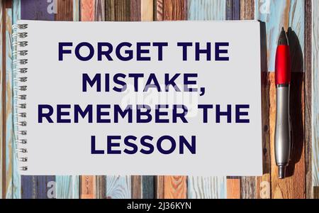 Motivierendes und inspirierendes Zitat – Vergessen Sie den Fehler, erinnern Sie sich an die Lektion, die auf einem Notizblock auf einem gestreiften Hintergrund geschrieben wurde. Stockfoto