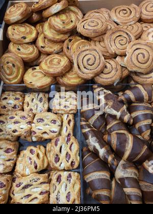 Frisch gebackenes, gefrorenes Blätterteig mit Marmelade und Frischkäse in der Bäckerei. Schokoladencroissants, Pudding und Zimtschnecken im Supermarkt. Frisches Dessert oder Nachmittagssnack Stockfoto