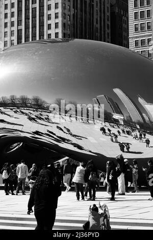 Menschen, die in schwarz-weißen Graustufen um die Bean Public Art im Millennium Park in der Innenstadt von Chicago, Illinois, stehen. Stockfoto