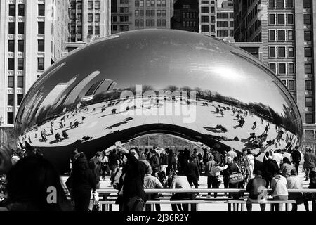 Menschen, die in schwarz-weißen Graustufen um die Bean Public Art im Millennium Park in der Innenstadt von Chicago, Illinois, stehen. Stockfoto