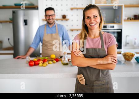 Das junge glückliche Paar genießt und bereitet gemeinsam gesunde Mahlzeiten in ihrer Küche zu Stockfoto