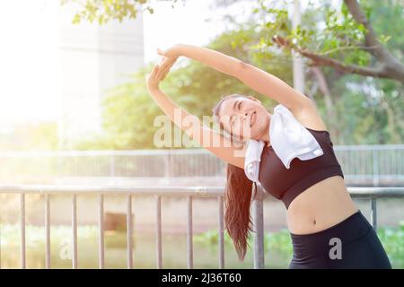 Asiatische gesunde Frau Schulter Stretching Übung im Freien Morgen Stockfoto