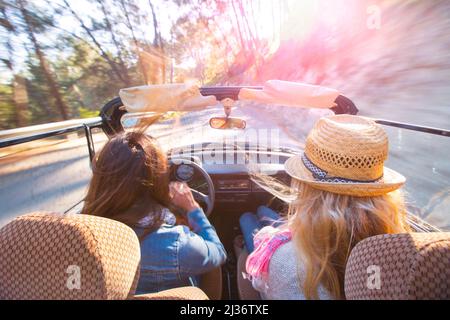 Freundinnen machen einen Roadtrip in einem klassischen VW-Käfer Stockfoto