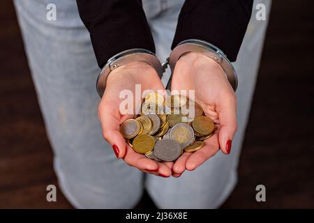 Frauen mit Handschellen und einer Handvoll Euro-Münzen Stockfoto