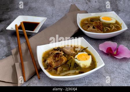 Einzelne Schalen mit Ramen, orientalische Suppe auf grauem Steingrund Stockfoto