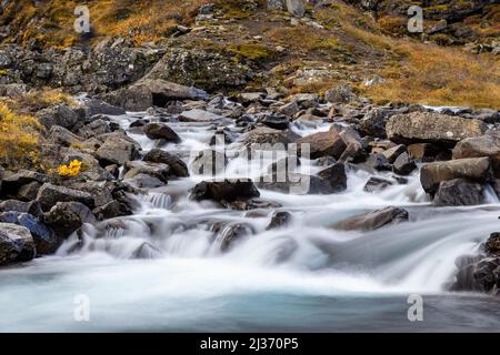 Detail des Folaldafoss Wasserfalls in den östlichen Fjorden, Island. Im Herbst wurde das eisige Wasser mit einer langen Exposition aufgenommen, die über das vulkanische Gestein tubbelte. Stockfoto