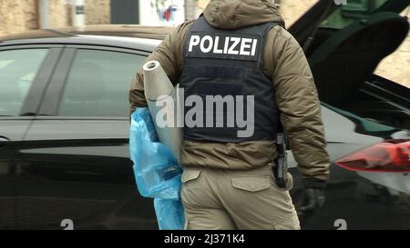 Eisenach, Deutschland. 06. April 2022. Ein Polizeibeamter trägt einen Gegenstand zu einem Auto vor dem Pub „Bull's Eye“. Die Ermittler haben seit dem Morgen Maßnahmen gegen mutmaßliche Rechtsextremisten ergriffen. Vier Personen aus dem Umfeld einer Kampfkunstgruppe in Eisenach seien verhaftet worden, sagte eine Sprecherin der Bundesanwaltschaft in Karlsruhe am Mittwoch. Quelle: Martin Wichmann TV/dpa/Alamy Live News Stockfoto