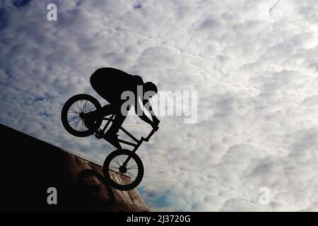 Silhouette eines jungen Mannes, der auf dem Fahrrad Extremsport betreibt. Hochwertige Fotos Stockfoto