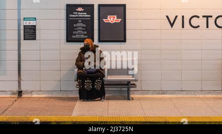 Eine muslimische Frau sitzt auf einer Bank und wartet auf einen TTC-U-Bahn-Zug auf dem Bahnsteig der Victoria Park U-Bahn-Station. Nahaufnahme. Die Toronto Transit Commission ist Stockfoto